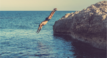 Man diving off cliff into water